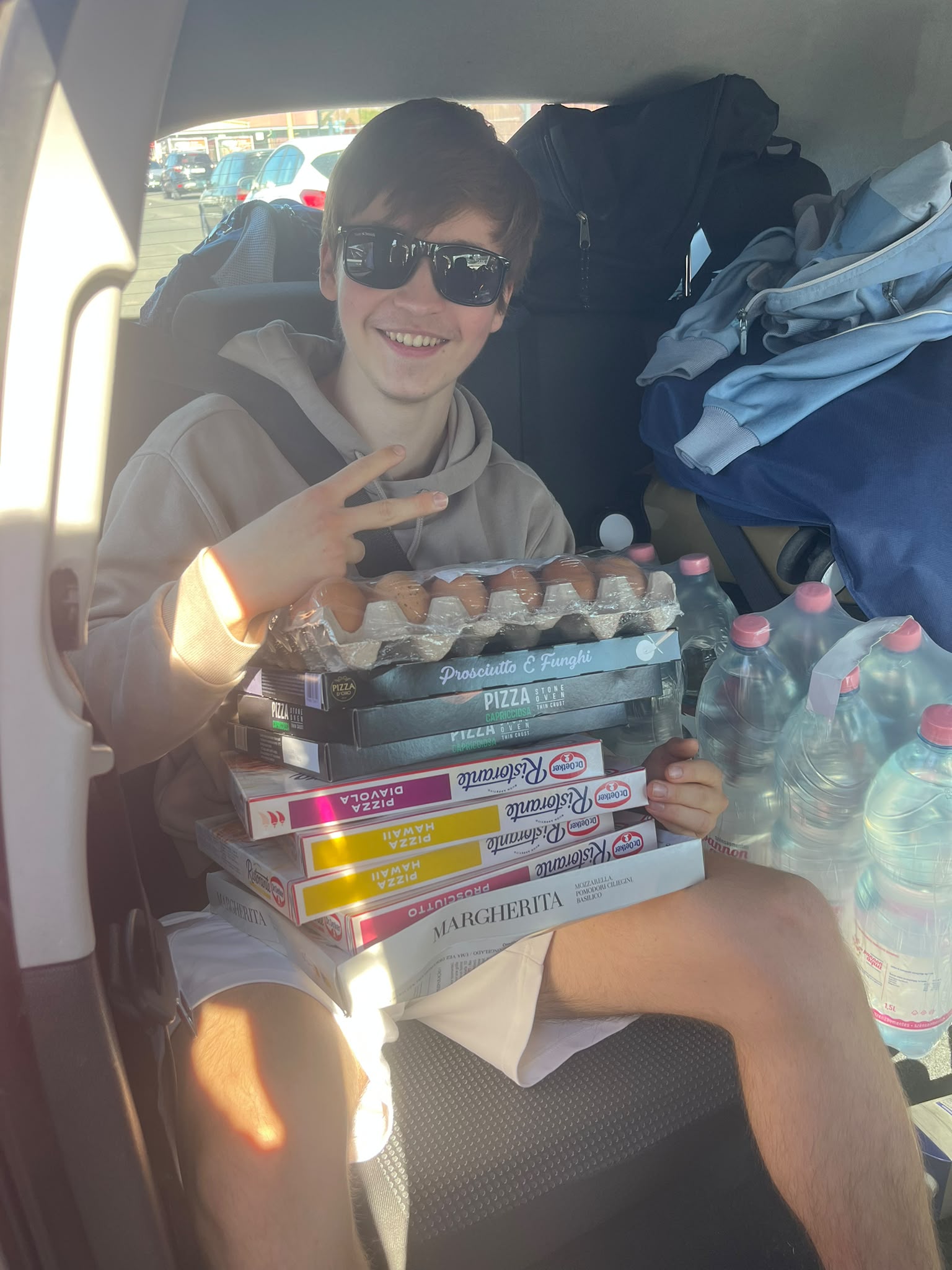 Mark im Auto mit einem Stapel Tiefkühlpizzen, Eiern und Wasserflaschen